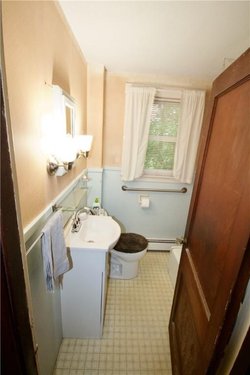 66 Beach St, Warren, RI 02885 - bathroom featuring baseboard heating, vanity, tile patterned floors, and a wainscoted wall