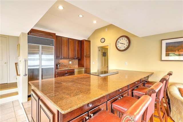 8 Alger Ave, Warwick, RI 02818 - kitchen with stainless steel appliances, light stone counters, a breakfast bar, lofted ceiling, and recessed lighting