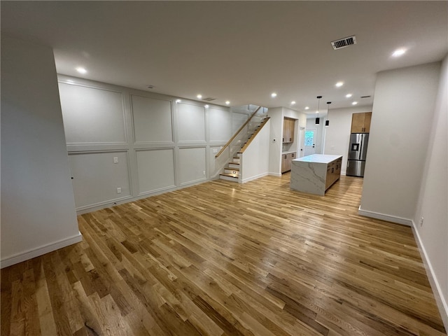 12 Daggett Ct Unit 2, Providence, RI 02906 - unfurnished living room with light wood-type flooring, stairs, a decorative wall, and recessed lighting