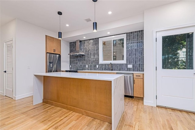 12 Daggett Ct Unit 2, Providence, RI 02906 - kitchen featuring appliances with stainless steel finishes, wall chimney exhaust hood, light wood-style flooring, light countertops, and backsplash