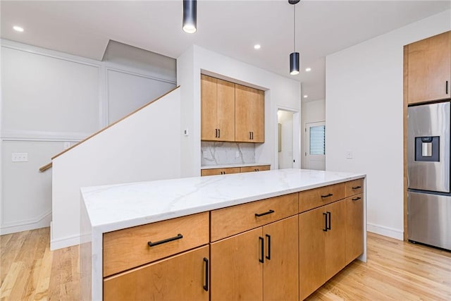 12 Daggett Ct Unit 2, Providence, RI 02906 - kitchen featuring stainless steel fridge with ice dispenser, light wood-type flooring, light stone counters, decorative backsplash, and pendant lighting