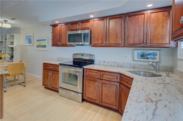 3399 Post Rd Unit 4, Warwick, RI 02886 - kitchen with stainless steel appliances, recessed lighting, light wood-type flooring, light stone counters, and brown cabinets
