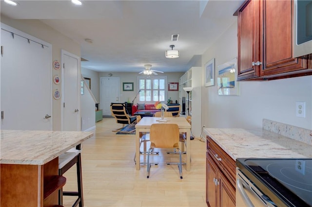 3399 Post Rd Unit 4, Warwick, RI 02886 - kitchen with open floor plan, ceiling fan, light wood-style flooring, a breakfast bar, and stainless steel microwave