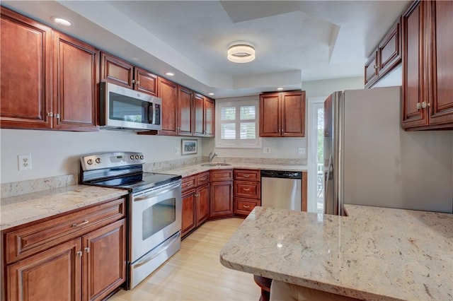 3399 Post Rd Unit 4, Warwick, RI 02886 - kitchen featuring appliances with stainless steel finishes, light stone counters, recessed lighting, light wood-type flooring, and brown cabinetry