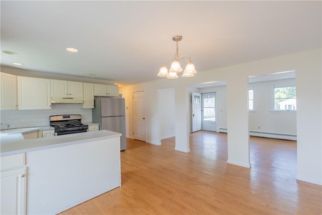 22 Gage St Unit 101, Providence, RI 02909 - kitchen with appliances with stainless steel finishes, under cabinet range hood, light countertops, a chandelier, and tasteful backsplash