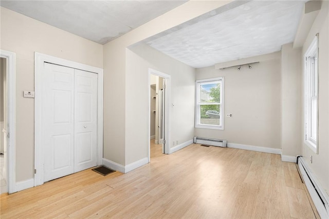423 Pine St, Central Falls, RI 02863 - unfurnished bedroom featuring a baseboard heating unit, light wood-style flooring, and a closet
