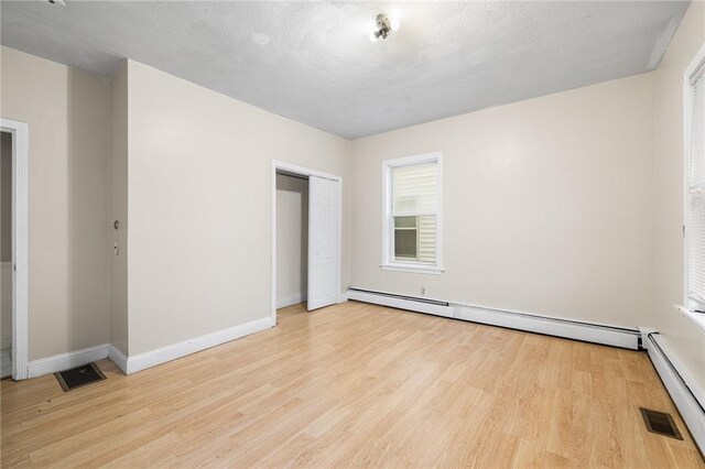 423 Pine St, Central Falls, RI 02863 - unfurnished bedroom with light wood-type flooring, a baseboard radiator, and a closet