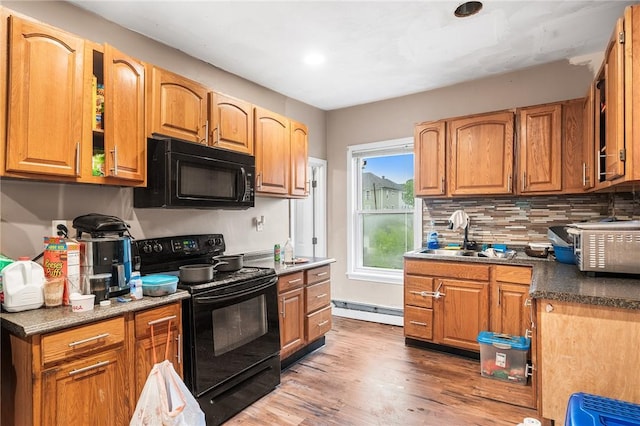 423 Pine St, Central Falls, RI 02863 - kitchen featuring black appliances, a baseboard heating unit, wood finished floors, backsplash, and brown cabinets