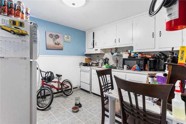 9 Nickerson St, Pawtucket, RI 02860 - kitchen with white appliances, under cabinet range hood, white cabinets, light countertops, and a wainscoted wall