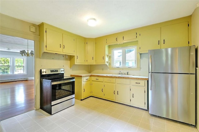 129 Ash St, Warwick, RI 02888 - kitchen featuring stainless steel appliances, cream cabinetry, light countertops, a baseboard heating unit, and a chandelier