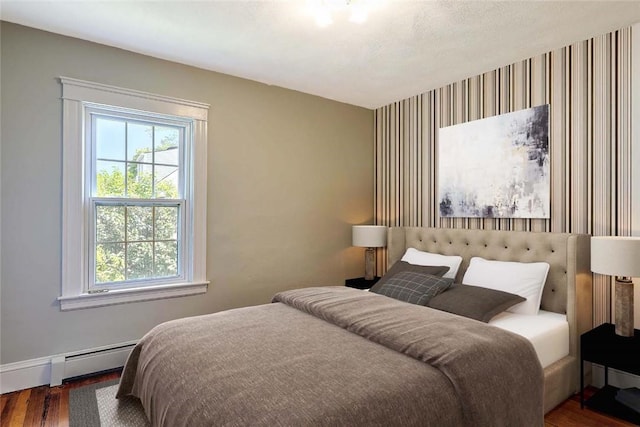 129 Ash St, Warwick, RI 02888 - bedroom with wood finished floors, an accent wall, a baseboard heating unit, and wallpapered walls