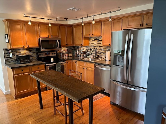 494 Woonasquatucket Ave Unit 304, North Providence, RI 02911 - kitchen with appliances with stainless steel finishes, dark countertops, light wood finished floors, tasteful backsplash, and brown cabinets