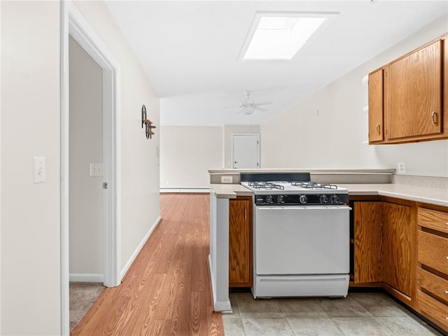 4430 Post Rd Unit 68E, Warwick, RI 02818 - kitchen with gas range gas stove, brown cabinetry, light countertops, a peninsula, and a ceiling fan