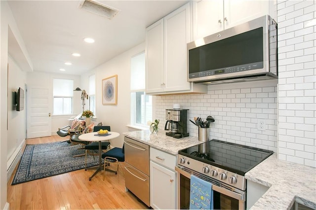 12 Poplar St, Newport, RI 02840 - kitchen featuring appliances with stainless steel finishes, light wood-style floors, white cabinetry, light stone countertops, and recessed lighting