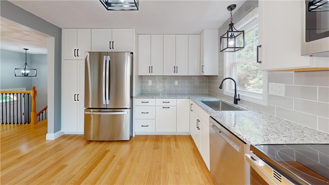 112 Cranberry Ridge Rd, Glocester, RI 02857 - kitchen with appliances with stainless steel finishes, light wood-style flooring, light stone counters, white cabinets, and tasteful backsplash