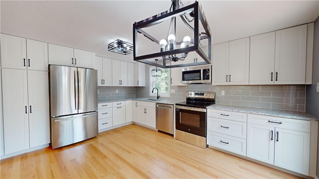 112 Cranberry Ridge Rd, Glocester, RI 02857 - kitchen with stainless steel appliances, a chandelier, light wood-type flooring, tasteful backsplash, and white cabinetry