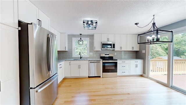 112 Cranberry Ridge Rd, Glocester, RI 02857 - kitchen with appliances with stainless steel finishes, light wood-style flooring, backsplash, white cabinetry, and a textured ceiling