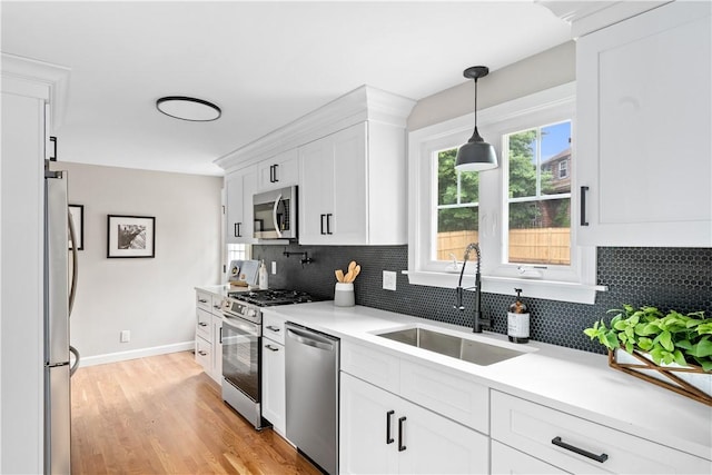 60 Webb Ave, Warwick, RI 02889 - kitchen featuring stainless steel appliances, white cabinets, backsplash, light countertops, and light wood-style floors