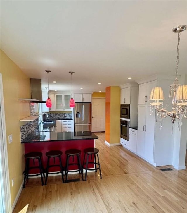 30 Hoover St, West Warwick, RI 02893 - kitchen with stainless steel appliances, a peninsula, light wood-type flooring, dark countertops, and recessed lighting