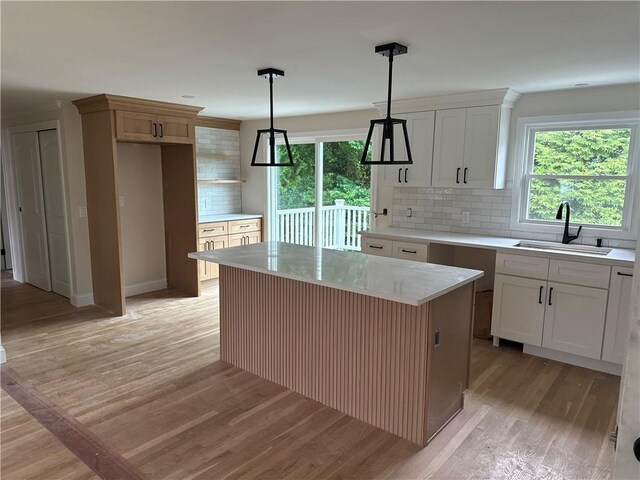199 First Ave, East Greenwich, RI 02818 - kitchen with light wood-style flooring, tasteful backsplash, light countertops, decorative light fixtures, and white cabinets