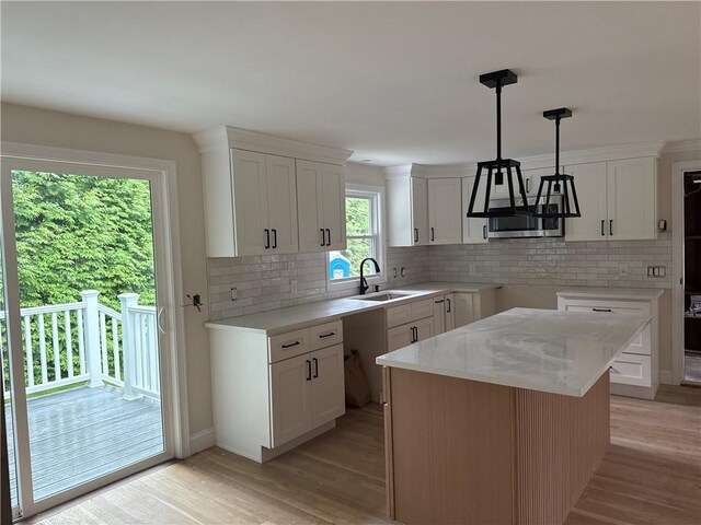 199 First Ave, East Greenwich, RI 02818 - kitchen featuring light wood finished floors, decorative backsplash, white cabinetry, hanging light fixtures, and light countertops