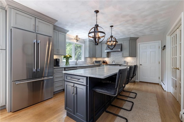 31 Wickaboxet Dr, West Greenwich, RI 02817 - kitchen with high quality fridge, gray cabinetry, under cabinet range hood, a chandelier, and tasteful backsplash