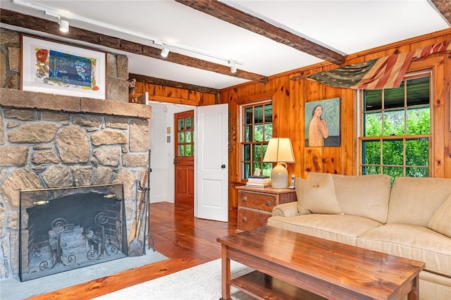 1049 Matunuck Schoolhouse Rd, South Kingstown, RI 02879 - living area featuring rail lighting, wood finished floors, beamed ceiling, wooden walls, and a stone fireplace