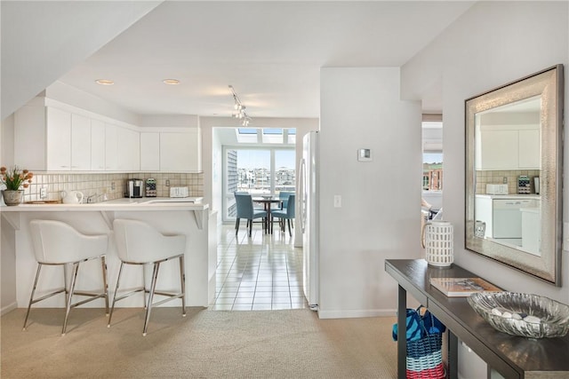 31 Coddington Unit 24, Newport, RI 02840 - kitchen with a breakfast bar area, light colored carpet, backsplash, light countertops, and white cabinets