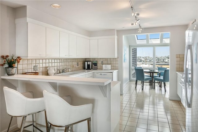 31 Coddington Unit 24, Newport, RI 02840 - kitchen featuring a kitchen bar, tasteful backsplash, light tile patterned flooring, light countertops, and a peninsula