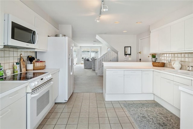 31 Coddington Unit 24, Newport, RI 02840 - kitchen featuring white appliances, light tile patterned floors, light countertops, white cabinets, and a peninsula