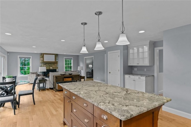 6 Jasons Grant Dr, Cumberland, RI 02864 - kitchen featuring a stone fireplace, white cabinetry, decorative light fixtures, glass insert cabinets, and light stone countertops