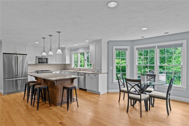 6 Jasons Grant Dr, Cumberland, RI 02864 - kitchen with appliances with stainless steel finishes, a kitchen bar, a kitchen island, light wood-style floors, and tasteful backsplash