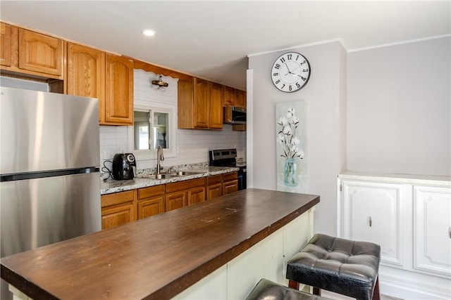 56 Park Ln, Coventry, RI 02816 - kitchen featuring appliances with stainless steel finishes, a kitchen bar, decorative backsplash, brown cabinetry, and recessed lighting