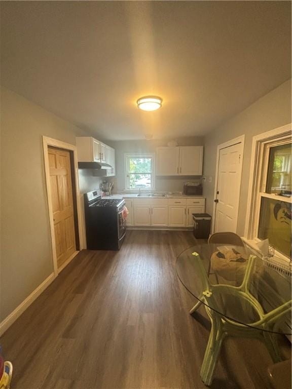 34 Lewis St, Central Falls, RI 02863 - kitchen with stainless steel range with gas cooktop, white cabinets, dark wood-type flooring, under cabinet range hood, and light countertops
