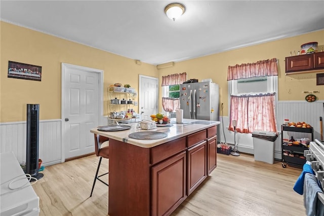 76 Slater St, Pawtucket, RI 02860 - kitchen with freestanding refrigerator, wainscoting, light wood-style floors, a kitchen breakfast bar, and a kitchen island