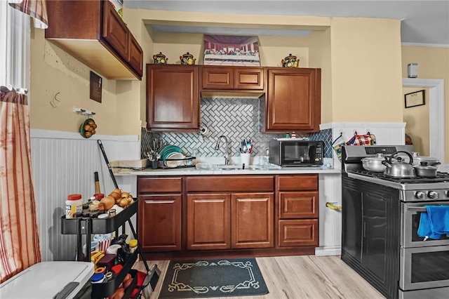 76 Slater St, Pawtucket, RI 02860 - kitchen with double oven range, black microwave, light countertops, wainscoting, and light wood-style flooring