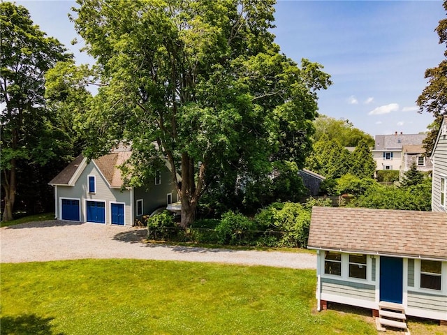 34 Pleasant St, North Kingstown, RI 02852 - view of front facade featuring gravel driveway, an outdoor structure, a front lawn, a garage, and a shingled roof