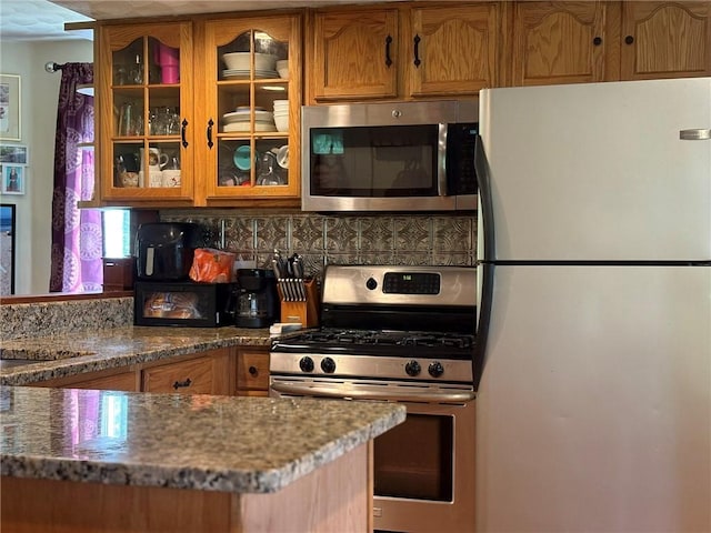 40 Anthony Rd, Foster, RI 02825 - kitchen with appliances with stainless steel finishes, glass insert cabinets, stone counters, backsplash, and brown cabinets