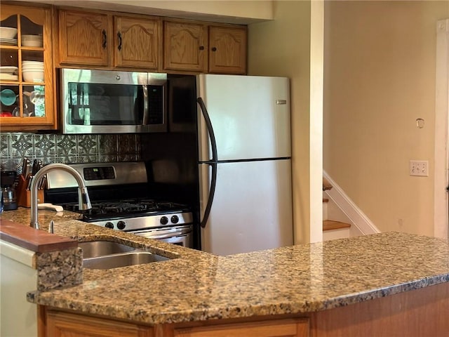 40 Anthony Rd, Foster, RI 02825 - kitchen with stainless steel appliances, backsplash, brown cabinetry, glass insert cabinets, and light stone counters