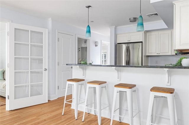 20 Narragansett Ave Unit 404, Narragansett, RI 02882 - kitchen featuring stainless steel fridge, a breakfast bar area, decorative light fixtures, light wood finished floors, and ornamental molding