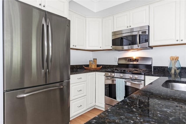 20 Narragansett Ave Unit 404, Narragansett, RI 02882 - kitchen with appliances with stainless steel finishes, white cabinetry, dark stone countertops, and light wood-style flooring