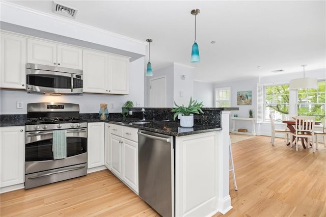 20 Narragansett Ave Unit 404, Narragansett, RI 02882 - kitchen with stainless steel appliances, light wood-style flooring, white cabinets, a peninsula, and hanging light fixtures