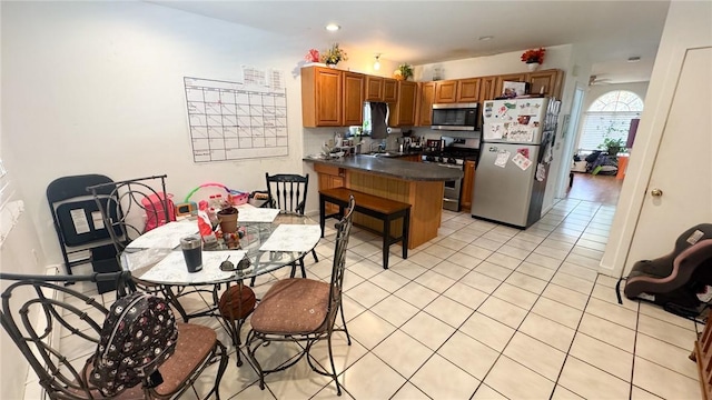 179 Wallace St, Providence, RI 02909 - kitchen featuring appliances with stainless steel finishes, a peninsula, dark countertops, brown cabinets, and light tile patterned flooring