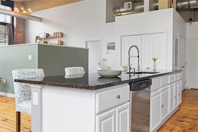 685 Social St Unit 114, Woonsocket, RI 02895 - kitchen with dishwasher, wood-type flooring, a kitchen island with sink, white cabinetry, and dark stone counters