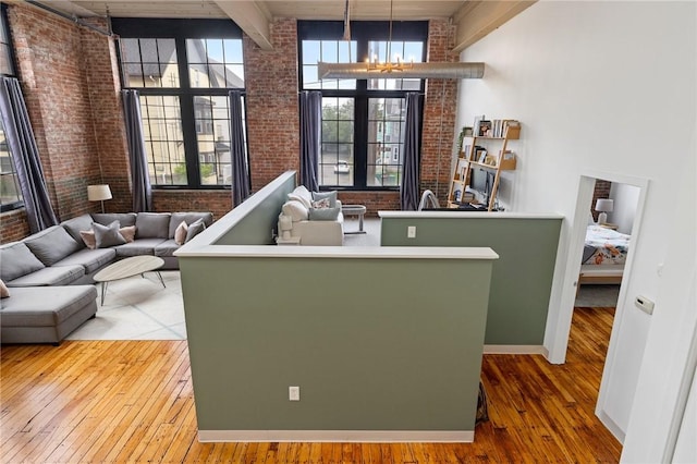 685 Social St Unit 114, Woonsocket, RI 02895 - living area with brick wall, hardwood / wood-style flooring, a chandelier, and a high ceiling