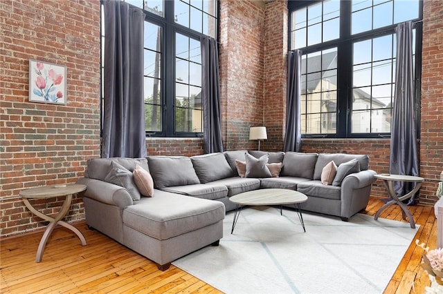 685 Social St Unit 114, Woonsocket, RI 02895 - living room featuring brick wall, wood-type flooring, and a towering ceiling
