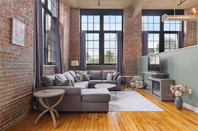 685 Social St Unit 114, Woonsocket, RI 02895 - living area featuring brick wall, wood-type flooring, a high ceiling, and a wood ceiling with exposed beams