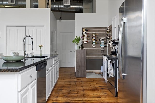 685 Social St Unit 114, Woonsocket, RI 02895 - kitchen featuring appliances with stainless steel finishes, dark wood-style floors, white cabinets, and dark stone countertops