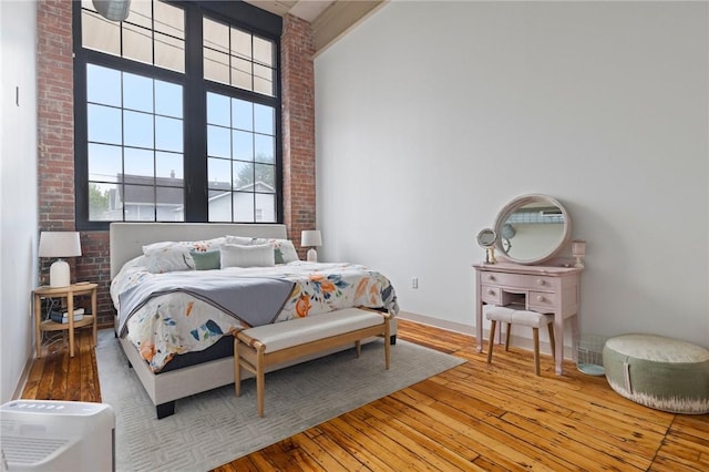685 Social St Unit 114, Woonsocket, RI 02895 - bedroom featuring hardwood / wood-style flooring, brick wall, and a high ceiling