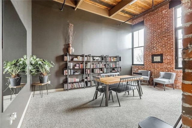 685 Social St Unit 114, Woonsocket, RI 02895 - dining room with a wooden ceiling with exposed beams, carpet flooring, brick wall, and a towering ceiling